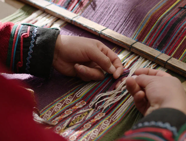 Hands of a Quechua woman weaving colorful blanket
