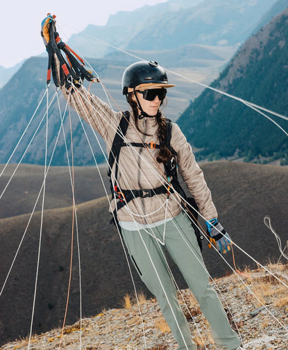 Person wearing Mayu ultralight PAKAFILL® alpaca jacket preparing to paraglide on a mountain ridge