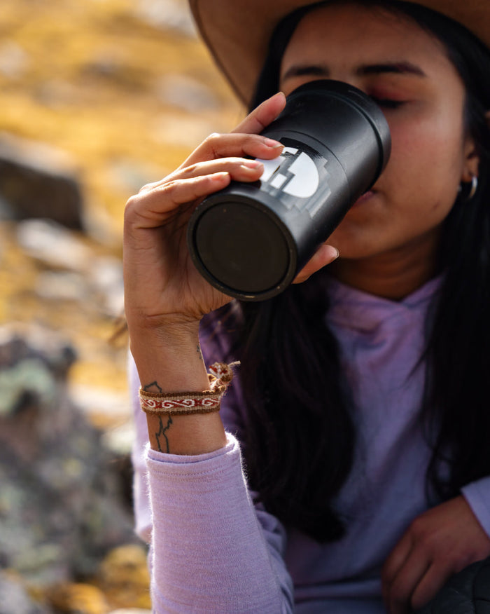 Woman Drinking from PAKA Mug Wearing Pacha / Brown Handwoven Quechua Alpaca Bracelet – PAKA Apparel