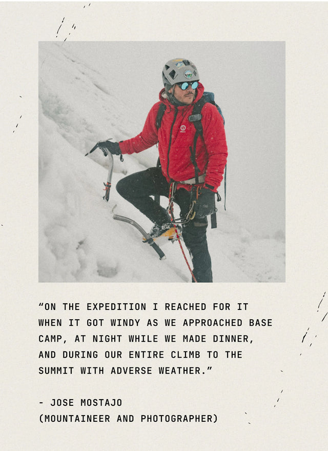 Person in a red jacket seated on a rocky mountain slope with a quote overlay reading ‘In the mountains I realize I’m...’