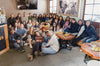 PAKA team and Quechua weavers gathered in a Peruvian weaving studio with looms and handwoven textiles