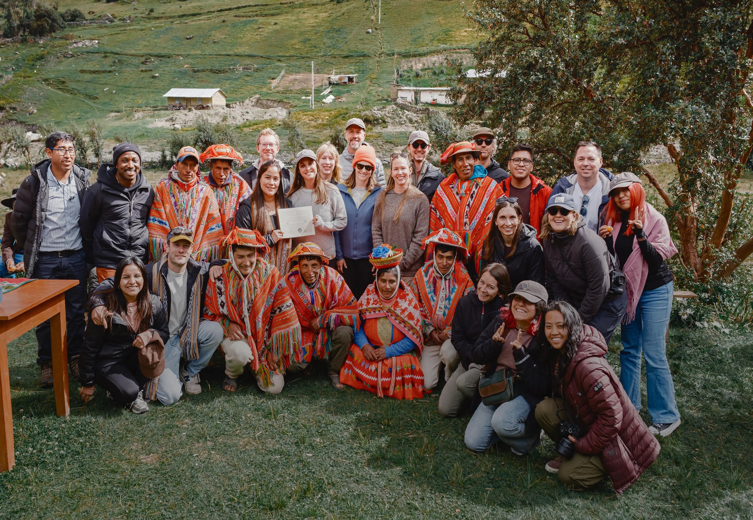 PAKA team and Quechua weavers pose together in a grassy Peruvian highland village