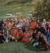 Group of PAKA team members and Quechua weavers posing together on a grassy Andes hillside near Cusco