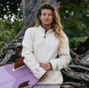 Woman seated outdoors wearing a cream PAKACLOUD fleece jacket in a relaxed fit