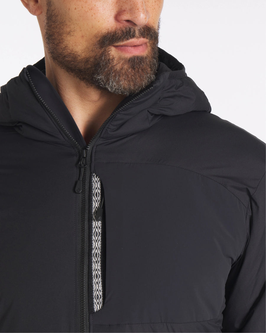 Close Up of Man Wearing Apu Lightweight Puffer in Black with Inca ID Near Zipper – PAKA Apparel