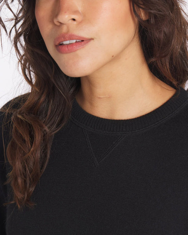 Close-up of The Lightweight Crew black alpaca sweater showcasing ribbed crewneck and V-stitch detail on white background