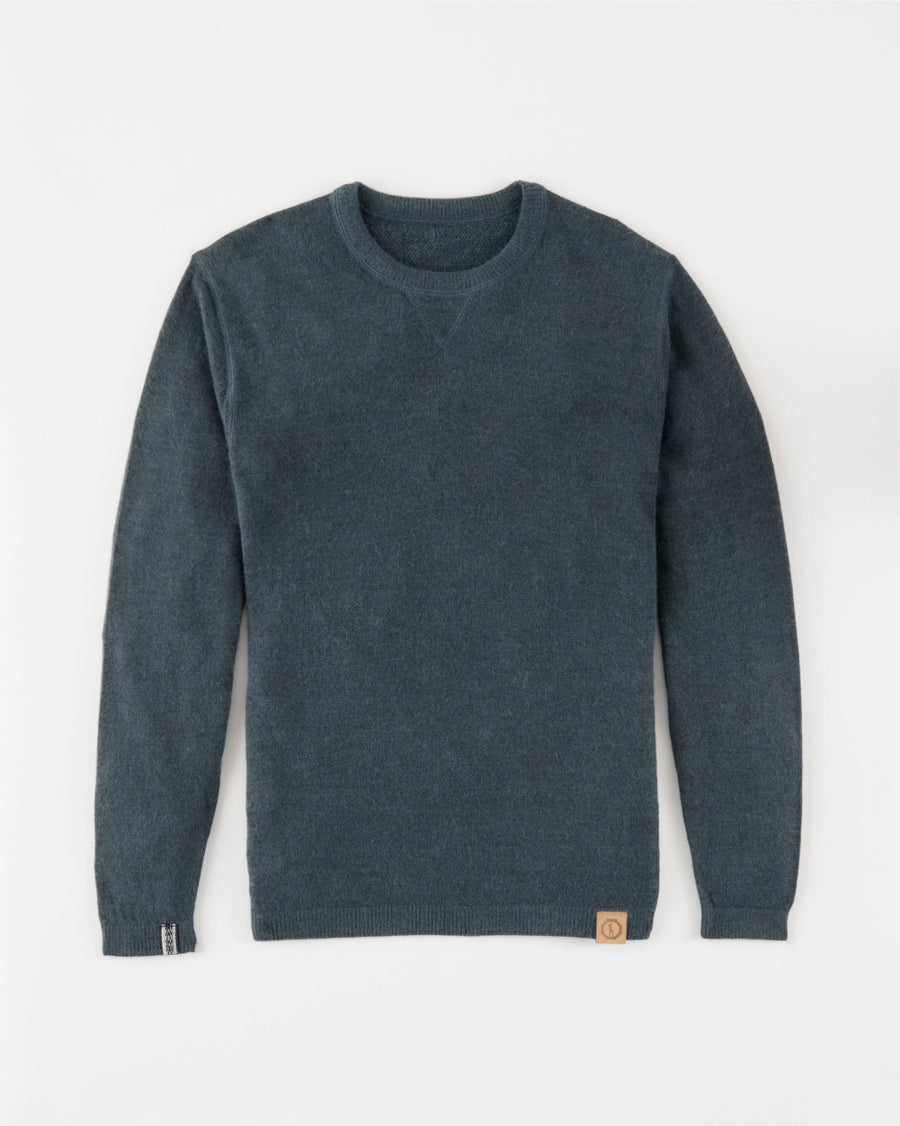 Flat-lay of The Lightweight Crew alpaca crewneck sweater in blue showing V-stitch collar and leather logo patch on white