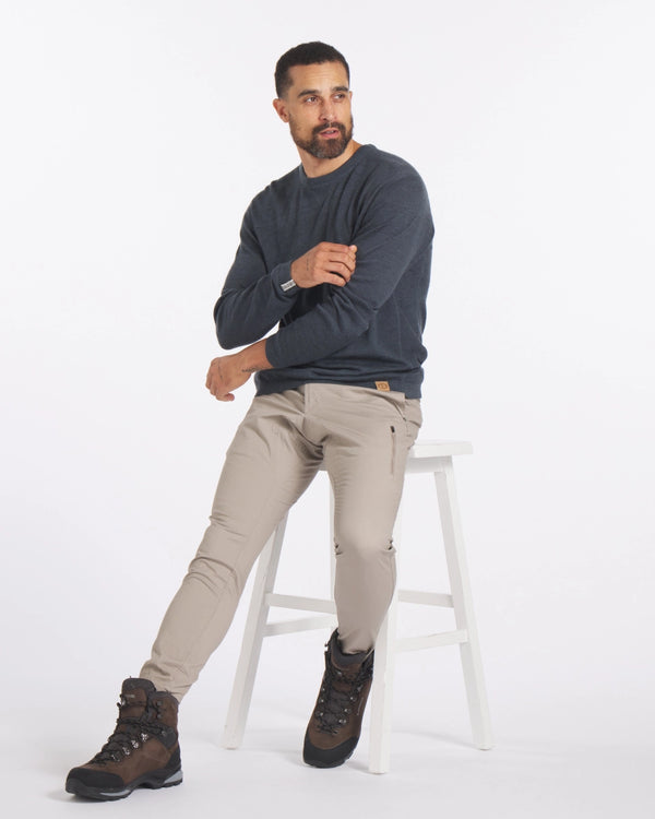 Seated three-quarter view of The Lightweight Crew sweater in blue on a male model showing relaxed fit and crew neckline against white background