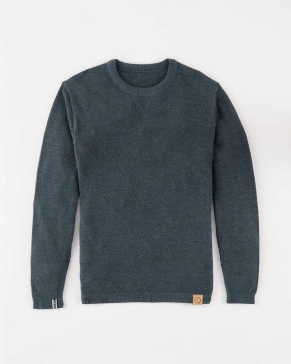 Flat-lay of The Lightweight Crew alpaca crewneck sweater in blue showing V-stitch collar and leather logo patch on white