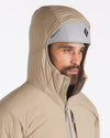 Three-quarter front view of Apu Lightweight Puffer jacket showing hood up over a helmet and raised zip collar on plain light gray background