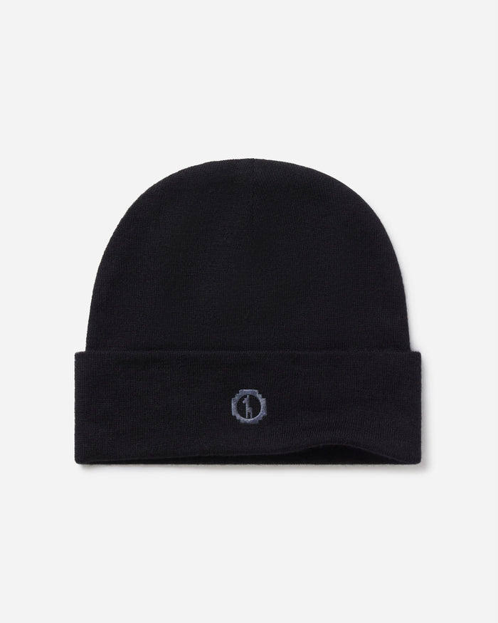 Top view of black cuffed beanie showing small embroidered logo on folded cuff against a light gray background
