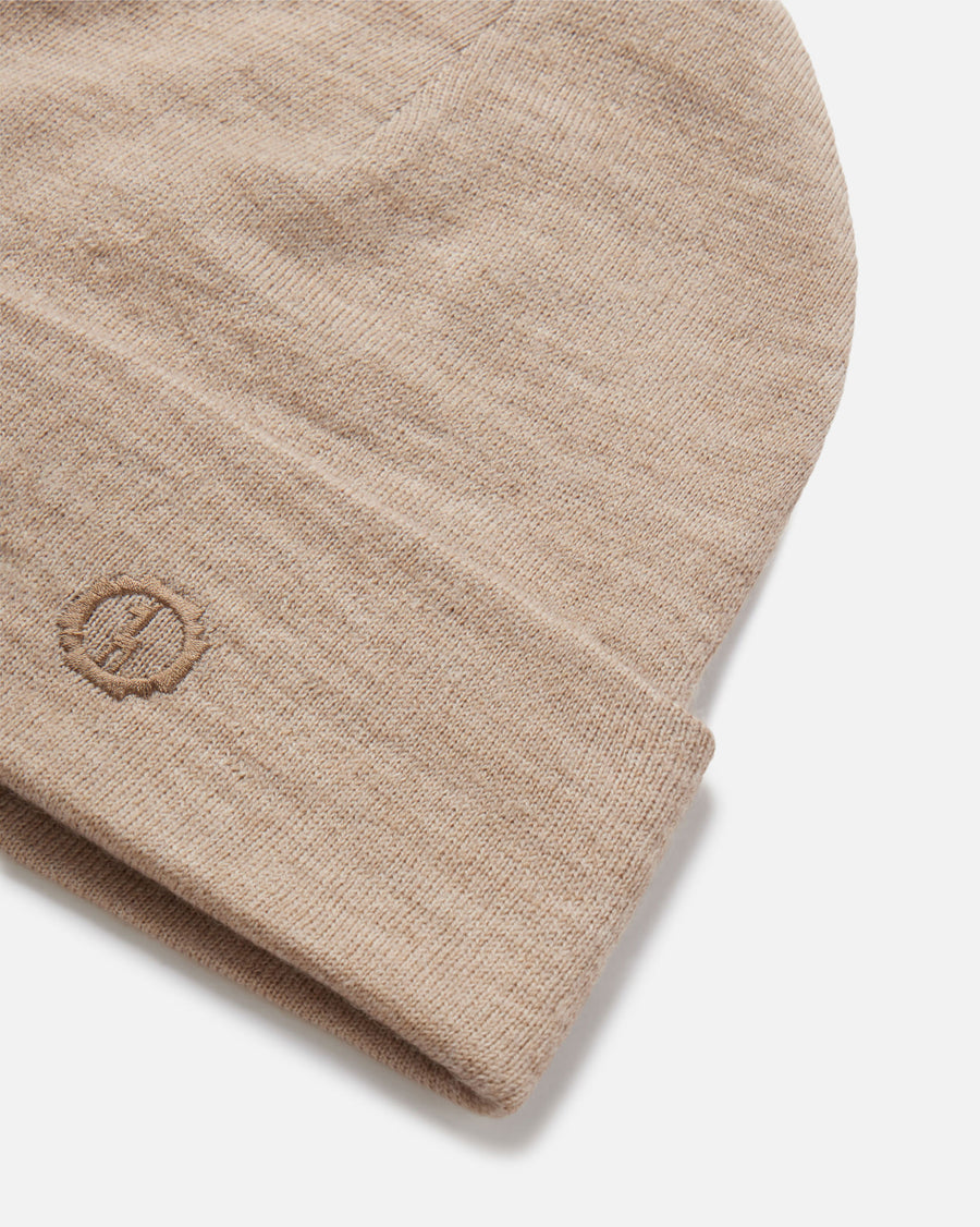 Close up of cuffed beanie showcasing rib knit alpaca wool in timber color and embroidered PAKA logo on white background