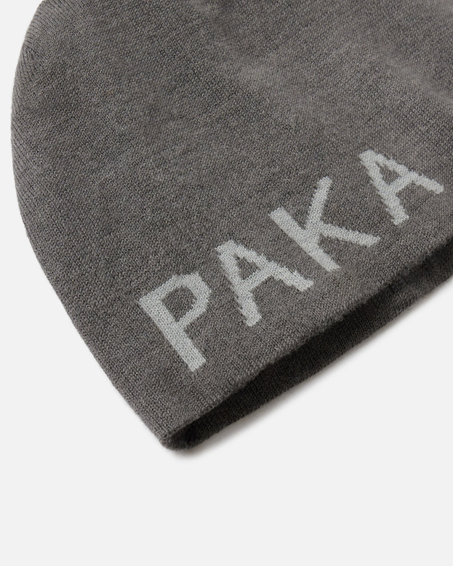 Close-up of skull cap beanie showcasing jacquard PAKA logo on gunmetal grey alpaca knit against white background