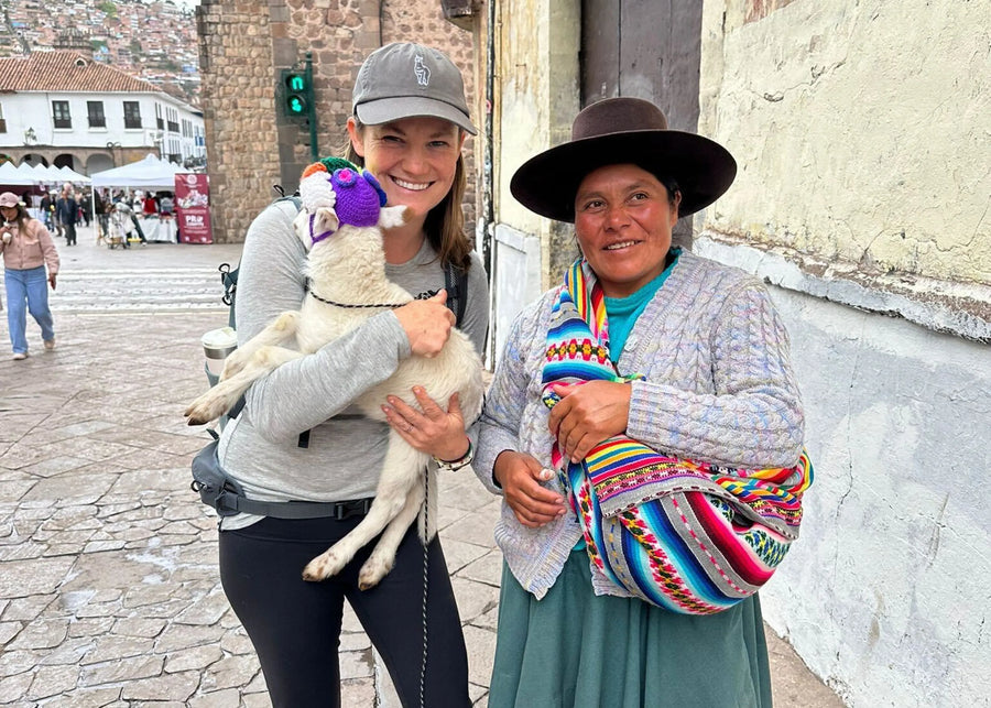 Two women standing on a street, one holding a small animal, with a colorful background.