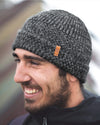 Side view of model wearing Cozy Marled Beanie in charcoal showcasing marled rib knit, folded cuff, and leather logo tag