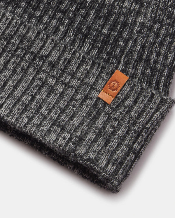 Close-up of a gray knit beanie with a brown leather patch on a white background
