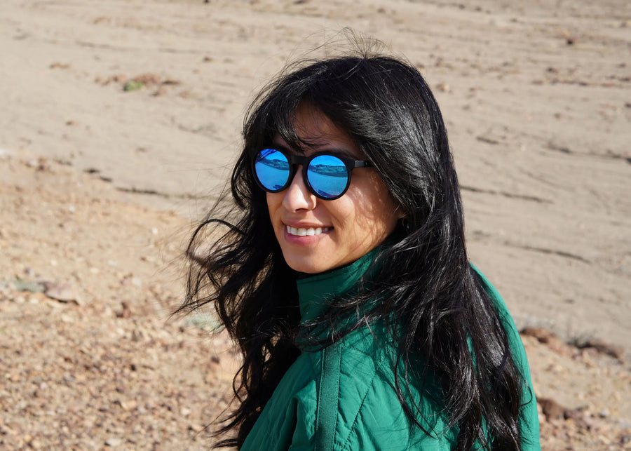 Woman wearing blue sunglasses and a green jacket