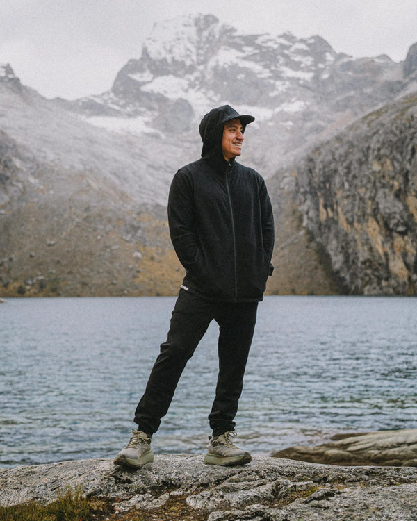 Three-quarter view of Men’s Breathe Joggers in black showing tapered fit and ankle cuffs in alpaca terry on a model by a mountain lake