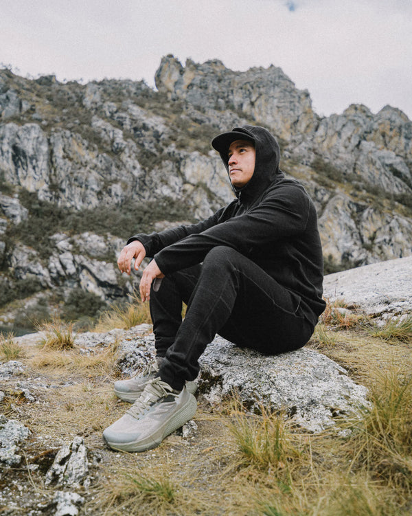 Three-quarter view of Men’s Breathe Joggers in black on a seated model showing tapered fit, ribbed cuffs, and alpaca terry fabric