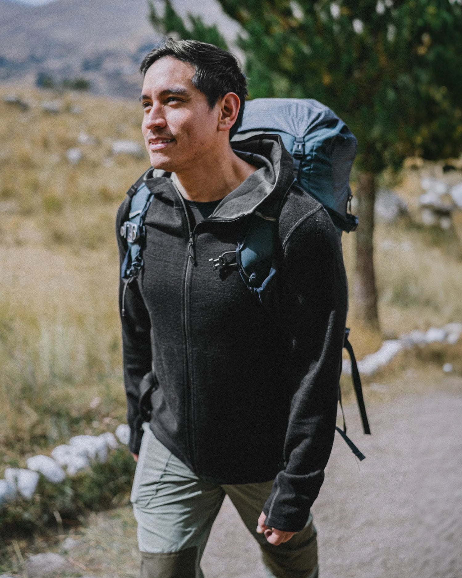 Three-quarter view of Men’s Breathe Full Zip Hoodie in black on a model, slim athletic fit with zippered pockets and thumbholes, hiking trail background