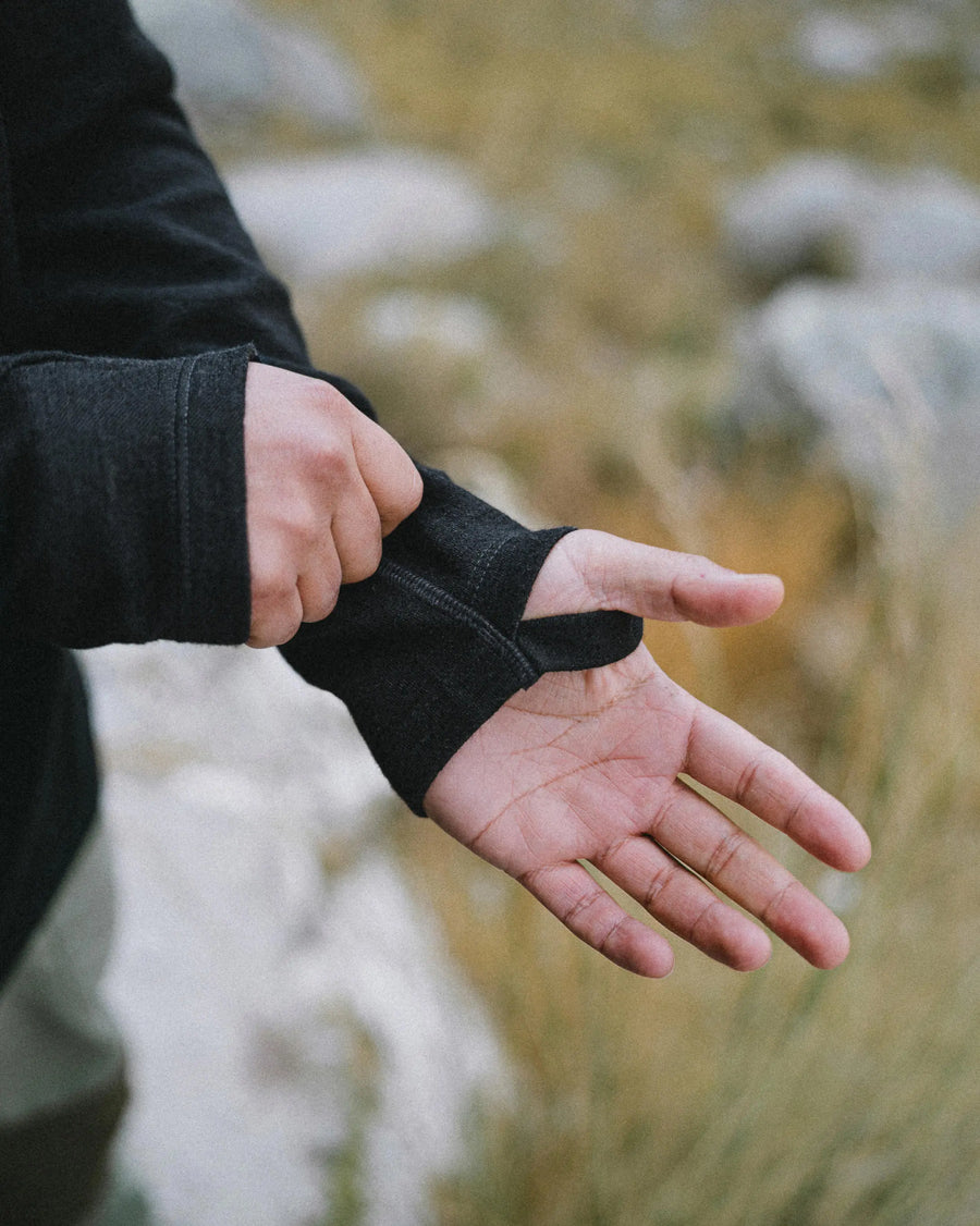 Close-up of Men’s Breathe Full Zip Hoodie sleeve showing thumbhole and cuff on a blurred outdoor background