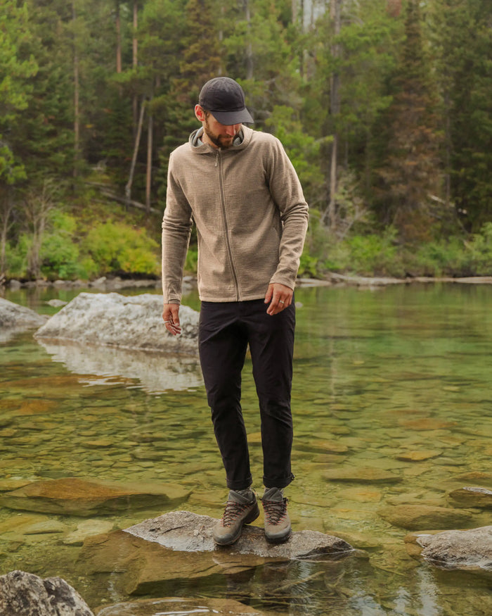 Man wearing timber Men’s Breathe full-zip hoodie, slim athletic fit, standing on rocks in a clear forest stream