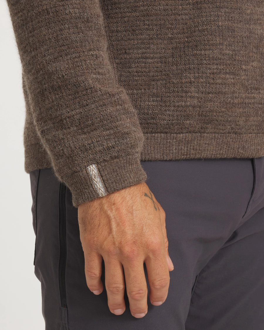 Close-up of Men’s Mountain Crew sweater sleeve showing ribbed hem, cuff tag, and brown two-tone alpaca knit on white background