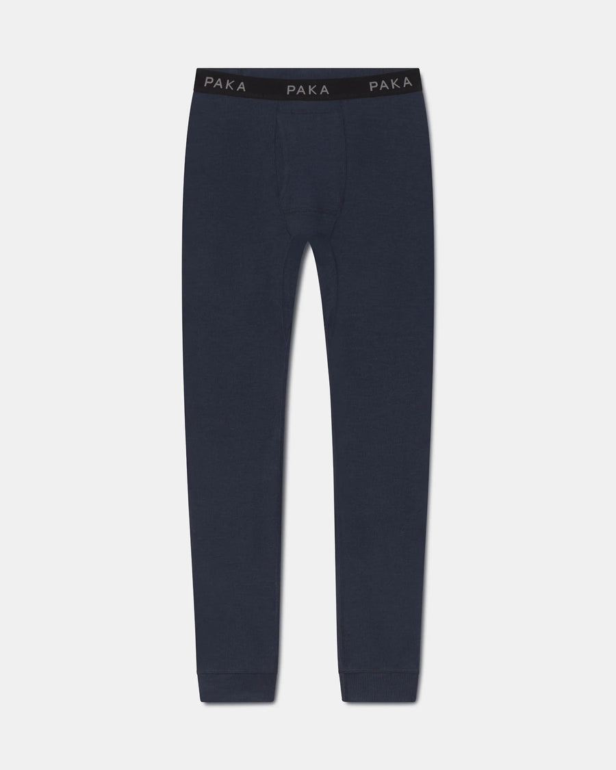 A pair of dark navy blue knit pants with a black elastic waistband featuring the brand name 'PAKA' printed in white, shown against a light gray background.