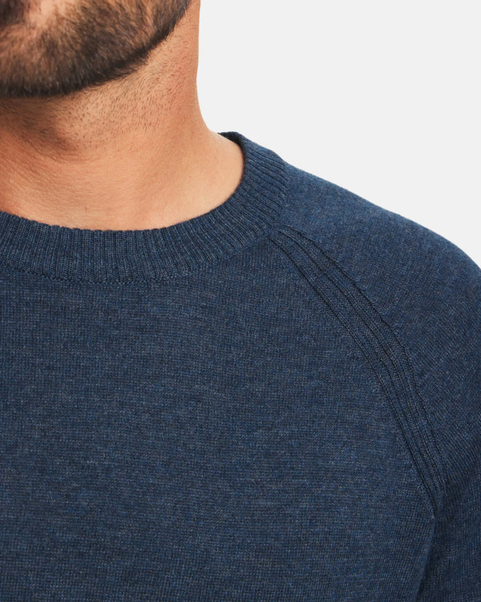 Close-up front of Men’s Ultralight Crew in navy showing ribbed crew neck, raglan shoulder seams, and fine knit texture on light gray background
