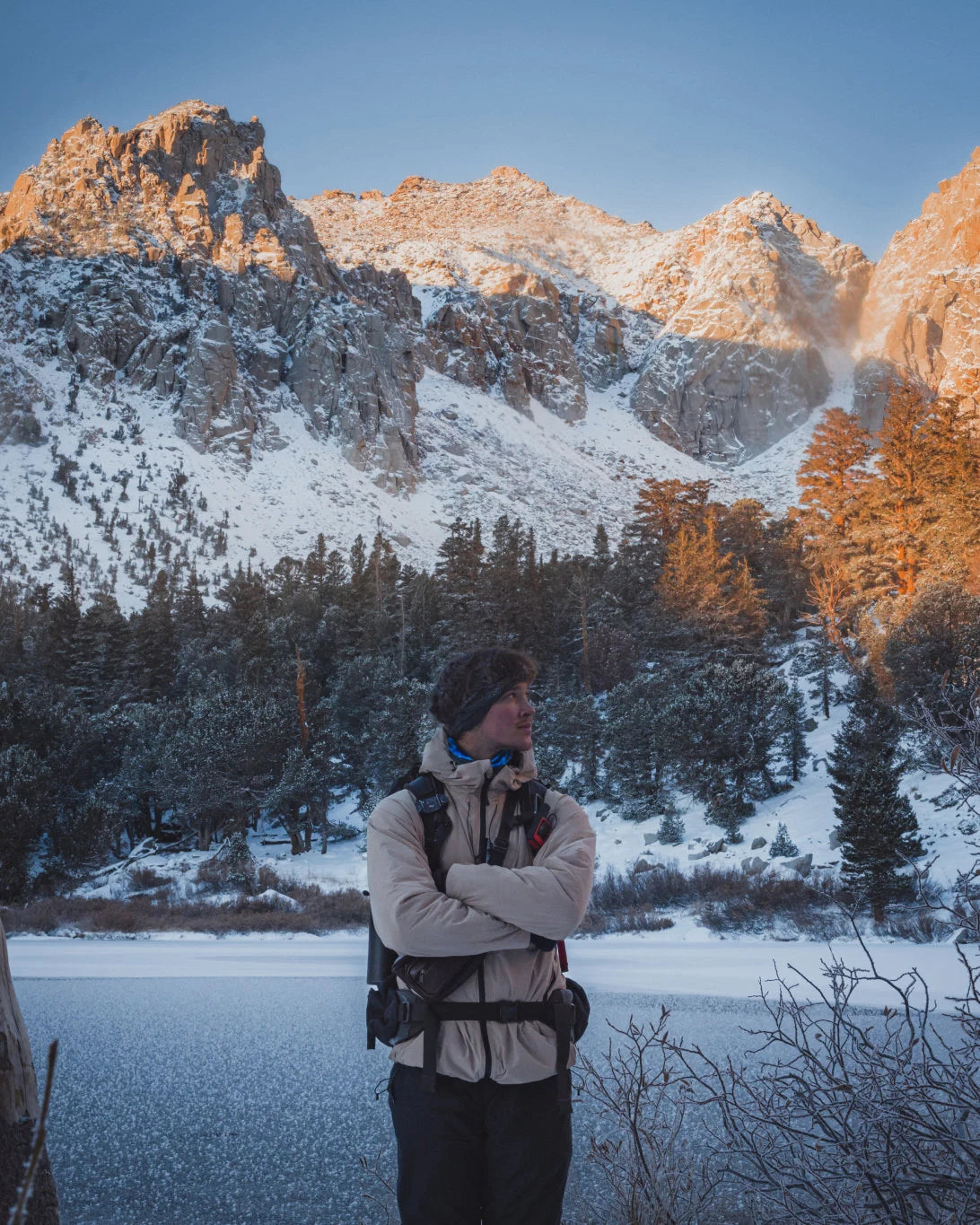 Man with Arms Crossed in Puma / Tan Apu Parka with Snowy Mountain and Lake in Background – PAKA Apparel