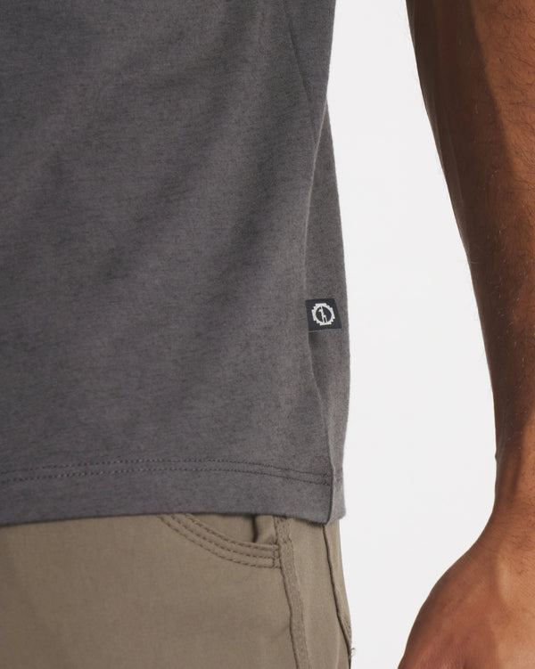 Side hem of charcoal Men’s Essential Tee showcasing PAKA side tag and straight hem against white background