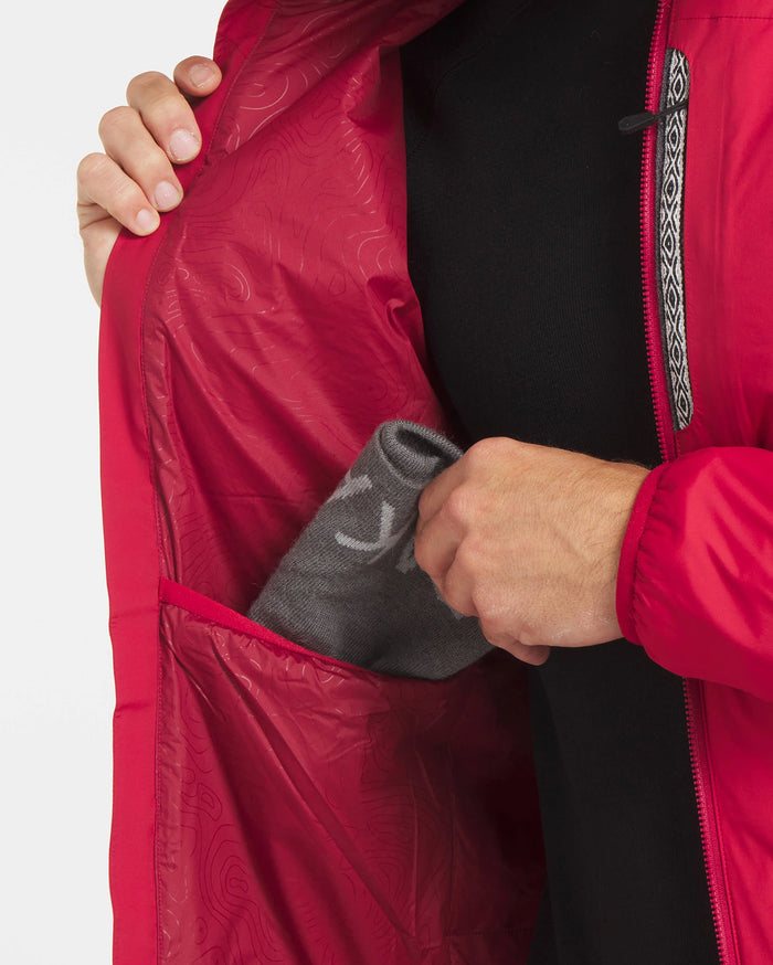 Close-up of Men’s Apu Lightweight Puffer jacket interior showcasing a large inner pocket with a hand placing a gray beanie, red exterior