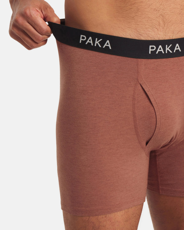 Brown boxer briefs with black waistband featuring 'PAKA' branding on a light gray background.