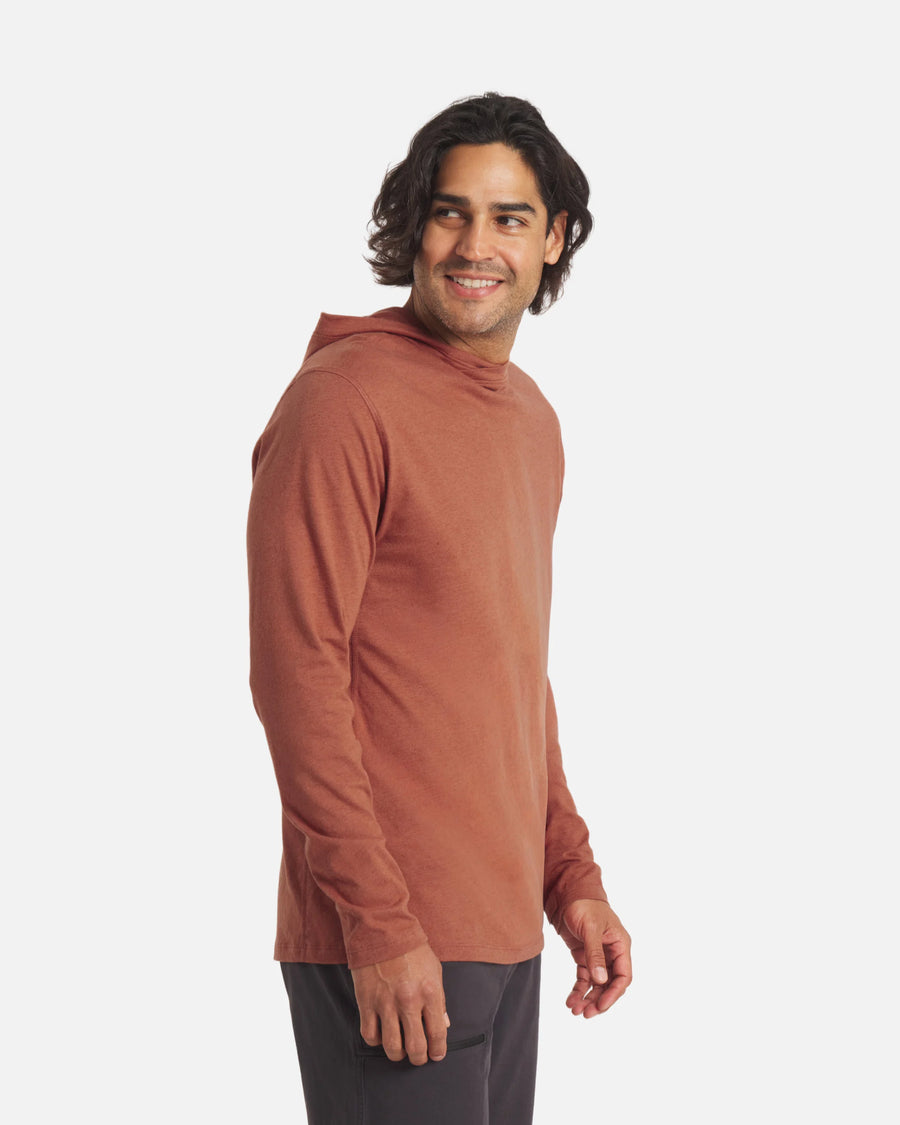 Three-quarter view of Men’s Sol Hoodie in cinnamon on a male model showing lightweight alpaca fabric, hood, and long sleeves against white background