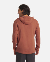 Back view of Men’s Sol Hoodie in cinnamon on model showing hood, long sleeves and alpaca fabric on light gray background