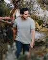 Three-quarter front of Men’s Essential Tee in willow green showing regular fit and crew neckline on a model outdoors