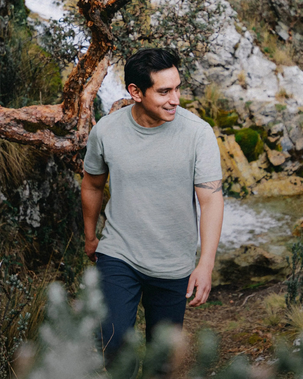 Three-quarter front of Men’s Essential Tee in willow green showing regular fit and crew neckline on a model outdoors