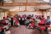 Peruvian weavers and community members gathered in a workshop displaying finished textiles and smiling