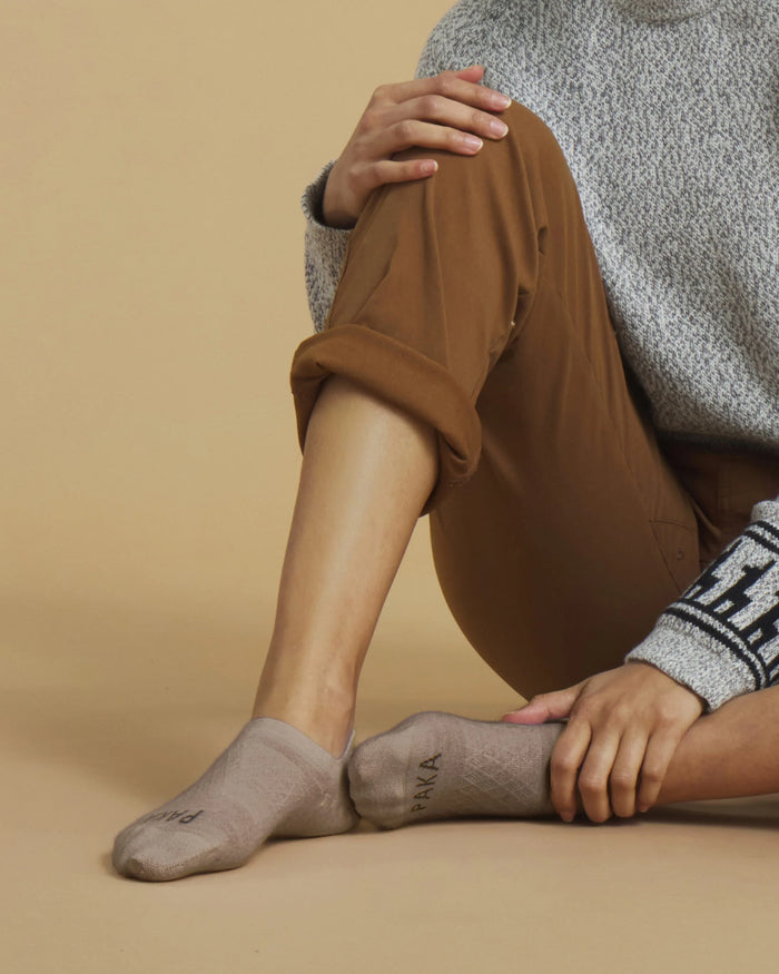 Side view of Alpaca No Show Socks in Timber showcasing low no-show profile and PAKA logo on sole with beige studio background