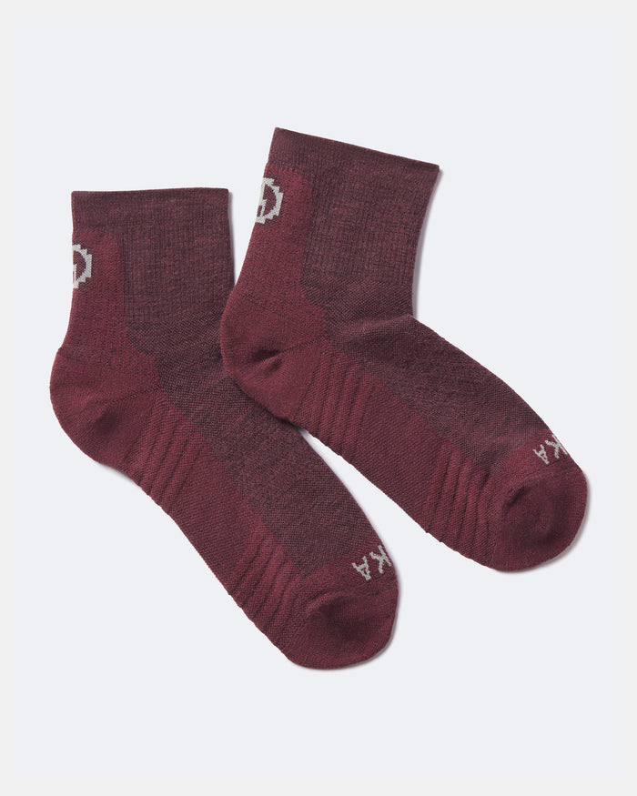 Angled view of Trail 1/4 Crew socks in maroon showing ankle-length fit and cushioned arch and toe on light gray background