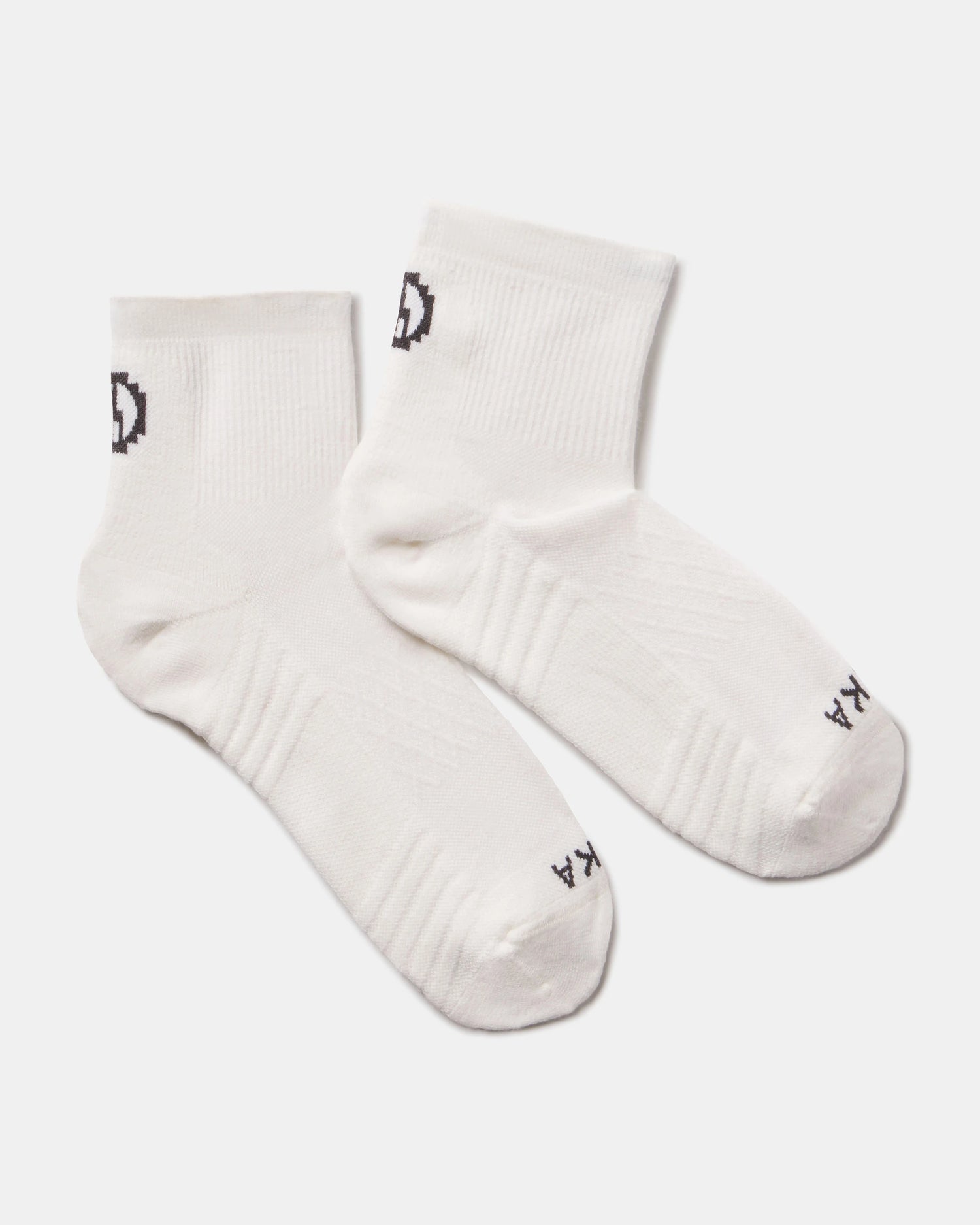Top-down view of Trail 1/4 Crew socks showcasing ankle height, ribbed arch support, and PAKA logo on light gray background