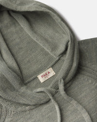 Close up overhead of women’s alpaca hoodie showing hood interior, drawstring, PAKA label and soft sage green knit on light background