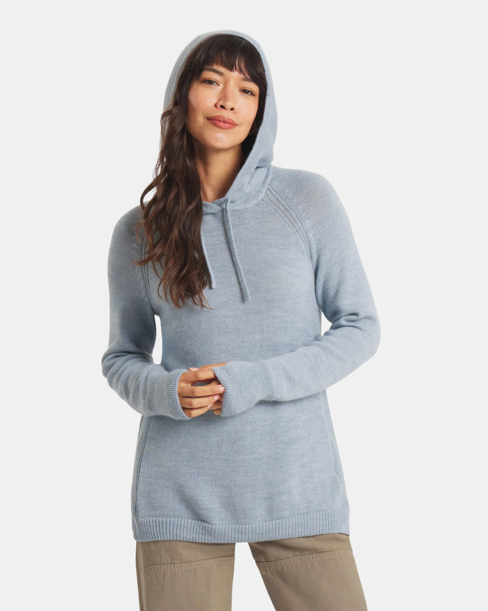 Front of women’s alpaca hoodie in light blue on model, relaxed fit with drawstring hood against a light gray background