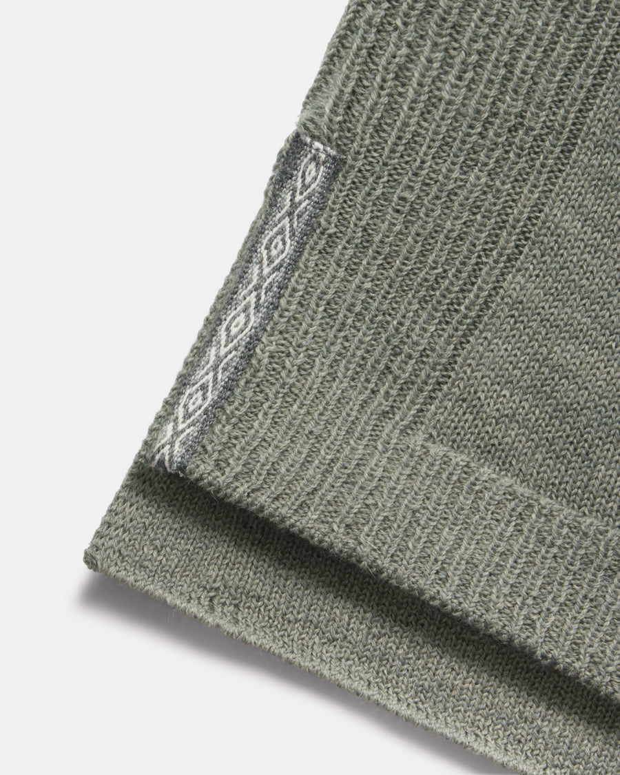 Close-up of hem of women’s alpaca hoodie showing ribbed knit and contrasting diamond-pattern side trim on white background