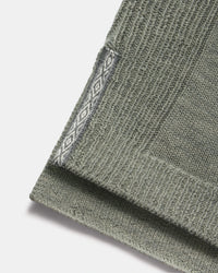 Close-up of hem of women’s alpaca hoodie showing ribbed knit and contrasting diamond-pattern side trim on white background