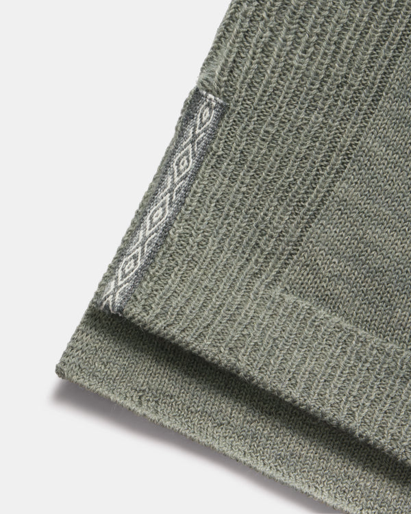 Close-up of hem of women’s alpaca hoodie showing ribbed knit and contrasting diamond-pattern side trim on white background