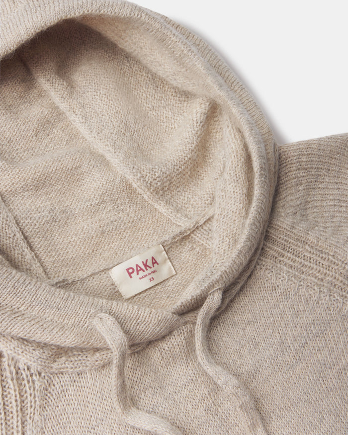 Close-up of women’s alpaca hoodie showing hood, drawstring, ribbed shoulder seam, and PAKA label on light background