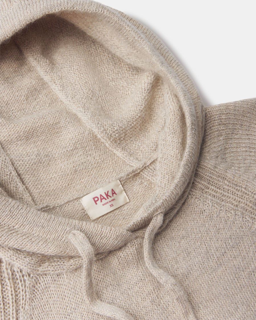 Close-up of women’s alpaca hoodie showing hood, drawstring, ribbed shoulder seam, and PAKA label on light background