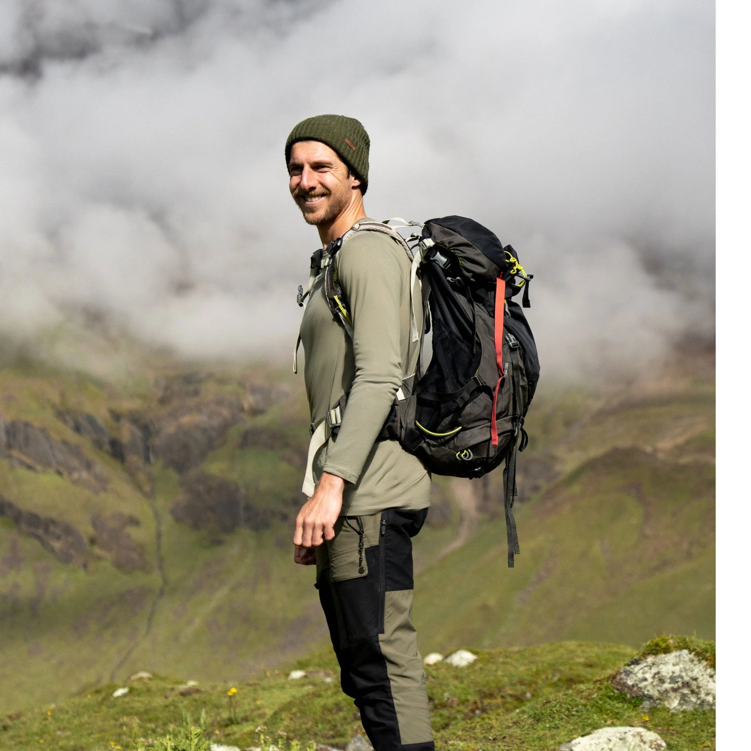 Man hiking with backpack wearing an Andean Moss alpaca Men’s Aire long sleeve shirt in cloudy mountains