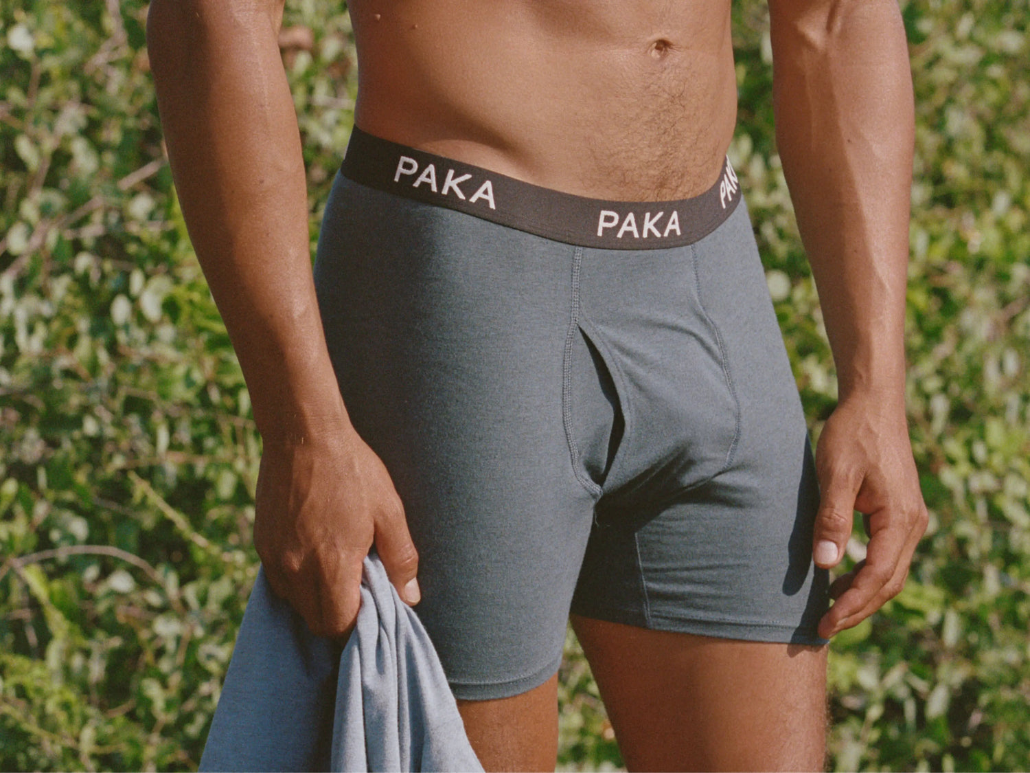 Close-up of men’s grey alpaca boxer briefs showing PAKA waistband and contour fly against leafy background